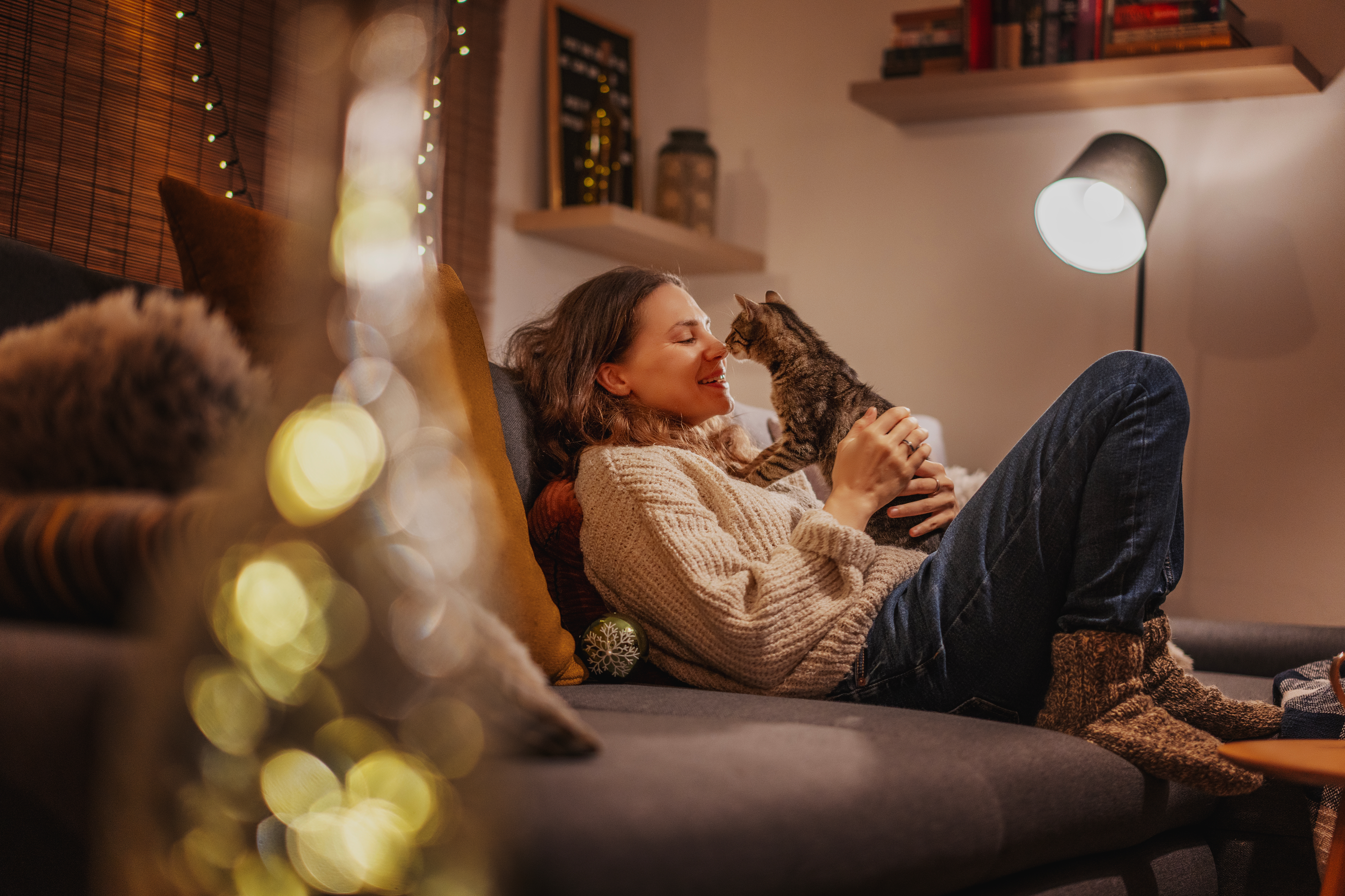 A woman relaxing on the sofa with her tabby cat in the evening