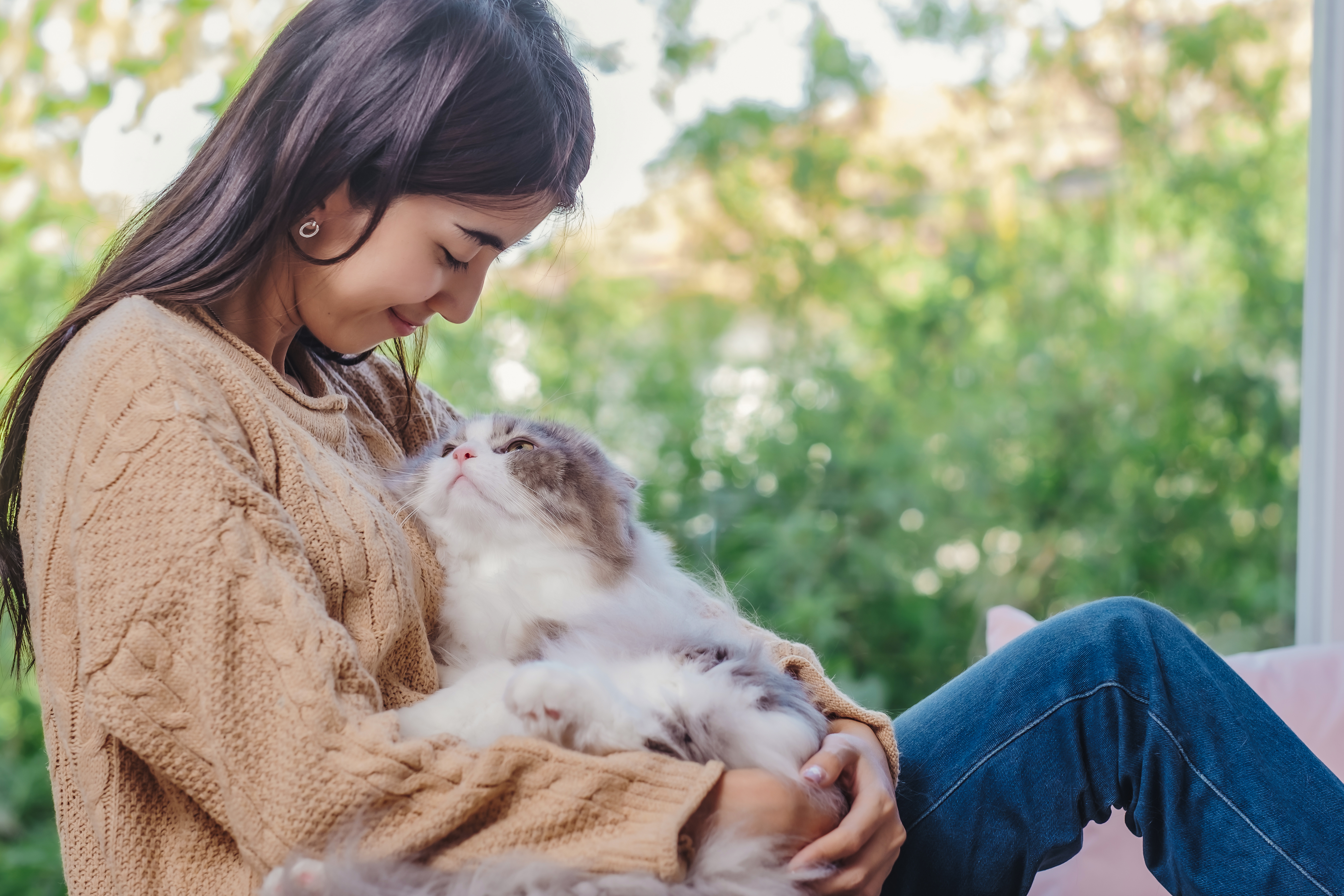 A woman holding her cat close in her lap